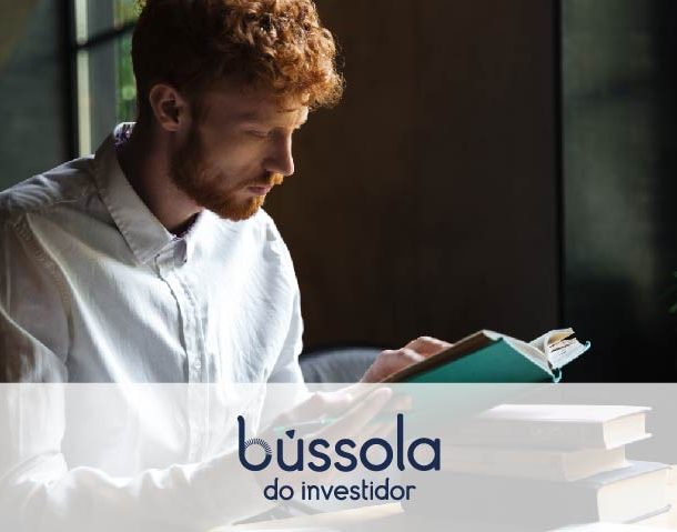 Homem lendo livros sobre investimentos