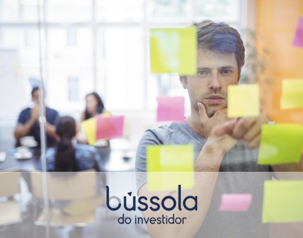 Homem parado na frente de post-it pensando em seu gerenciamento financeiro